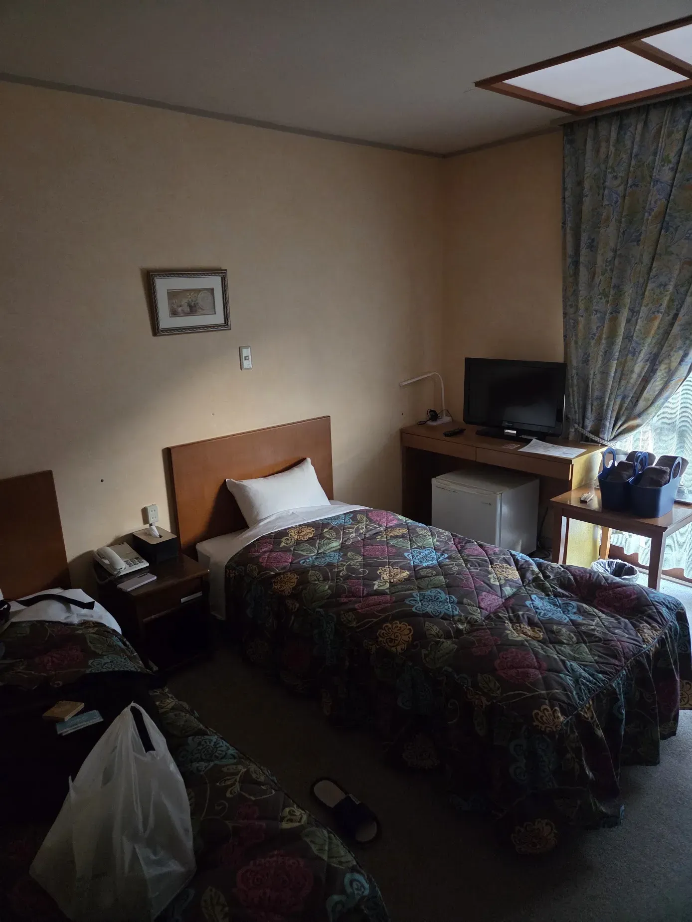 The 80s room in Shikoku: 2 twin beds with floral bedspreads, beige walls, old carpet and patterned curtains.