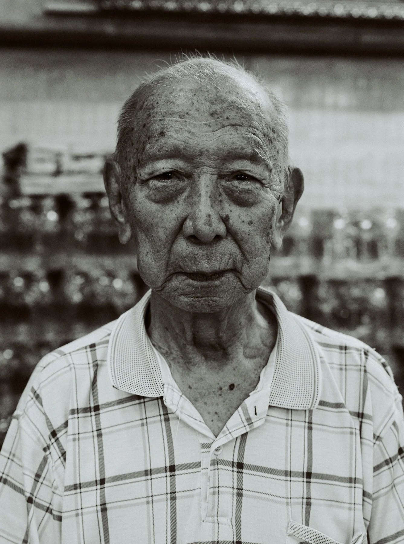Black-and-white portrait of an older man in a checked shirt in Bangkok