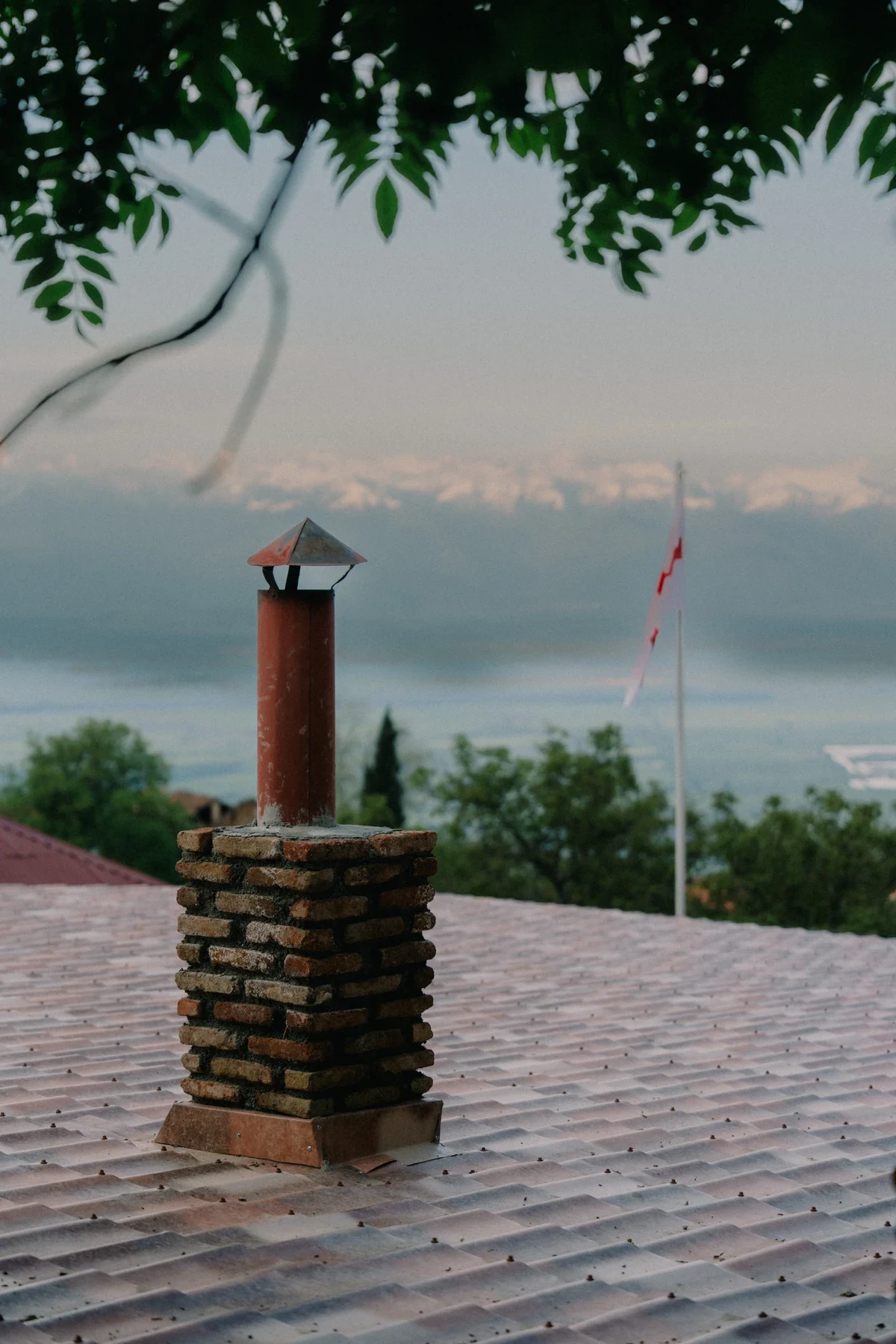 A stone chimney on a tiled terrace overlooking distant mountains in Georgia