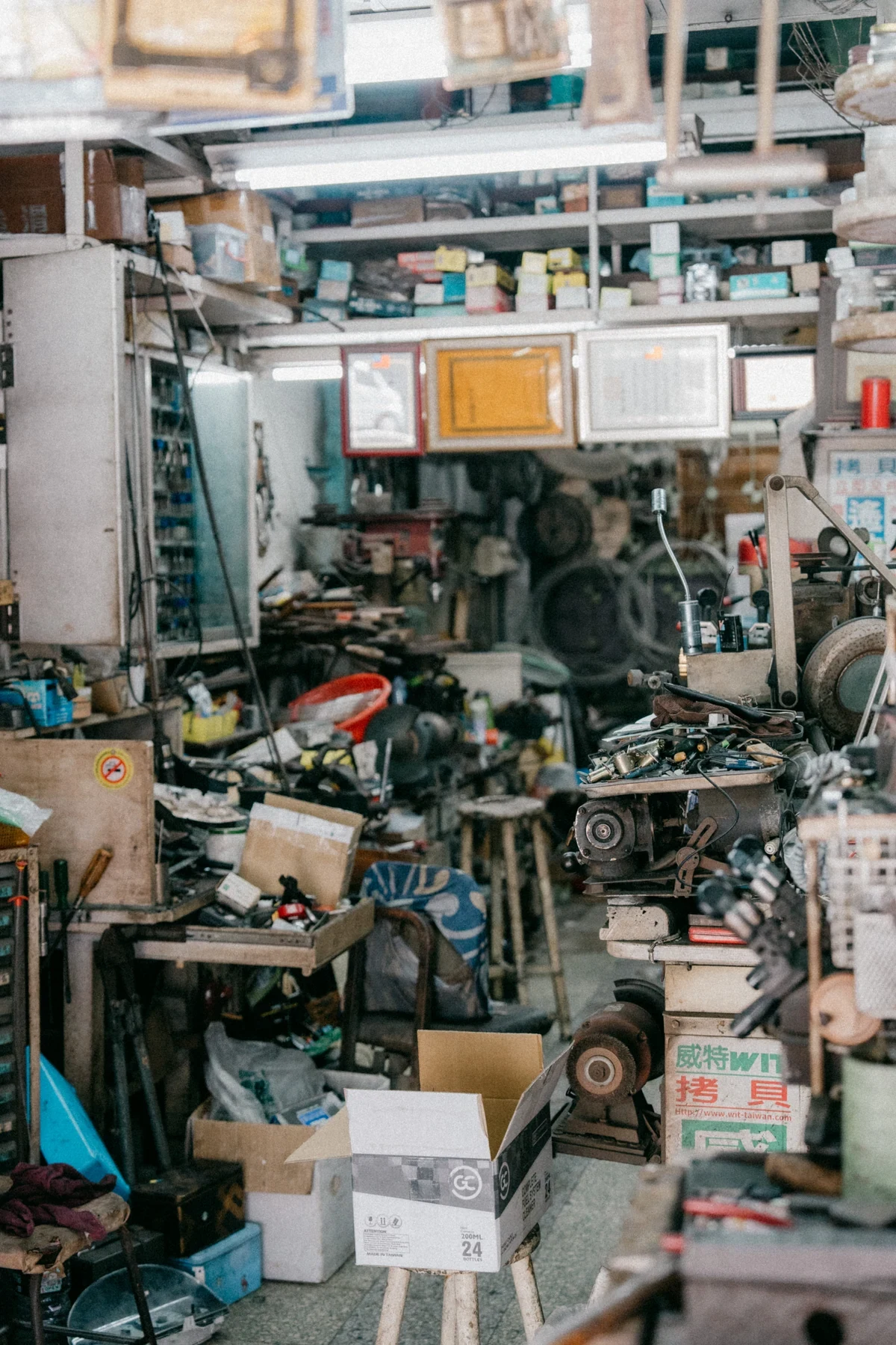 A densely packed workshop with tools, machinery, boxes and framed documents