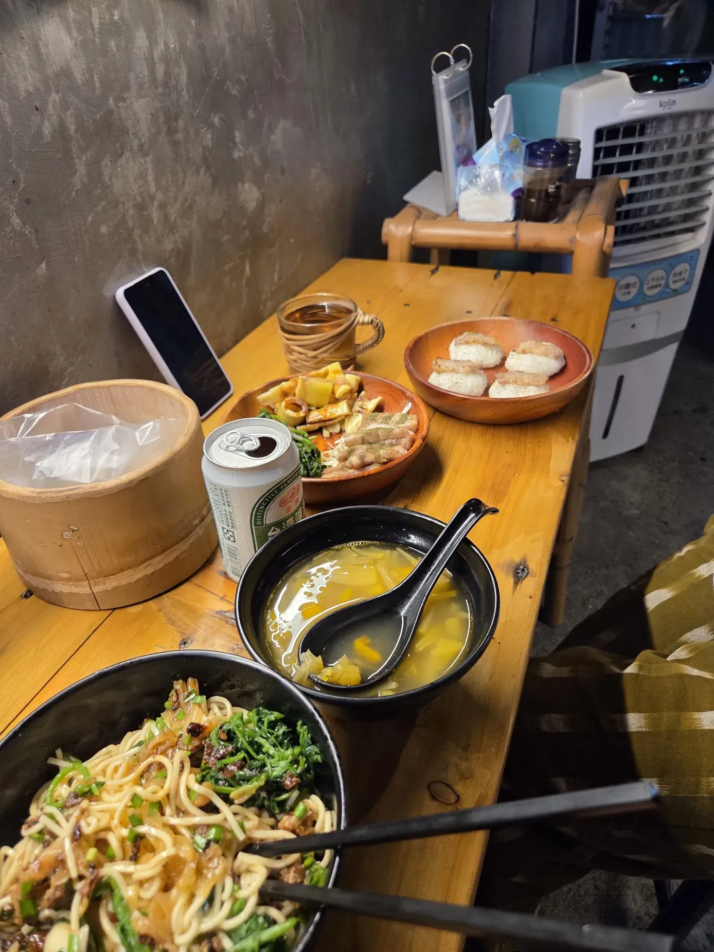 Dinner in Taiwan that week: noodles, soup, grilled skewers and a can of Taiwan Beer on a wooden table.