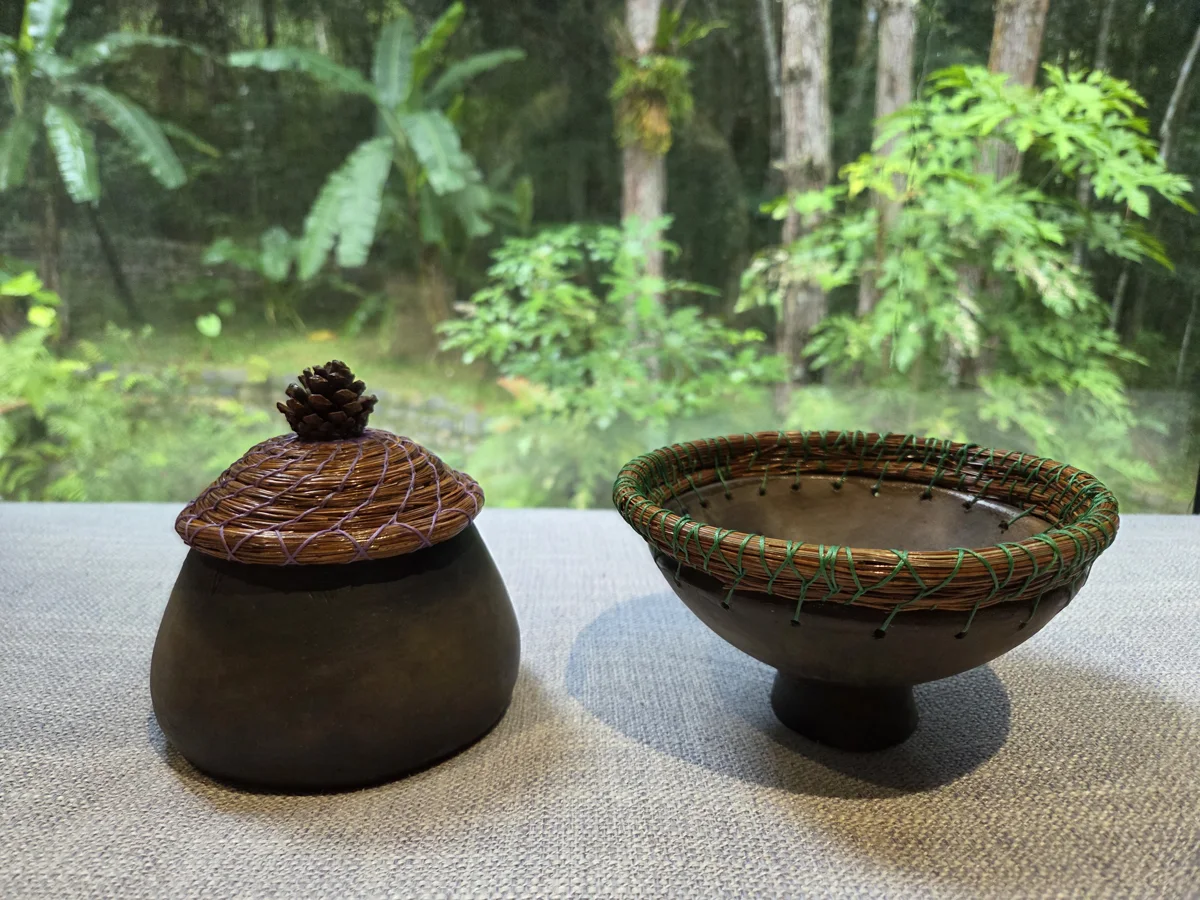 Handmade pine-needle lid and basket on pottery bowls, with the Da Lat forest behind them