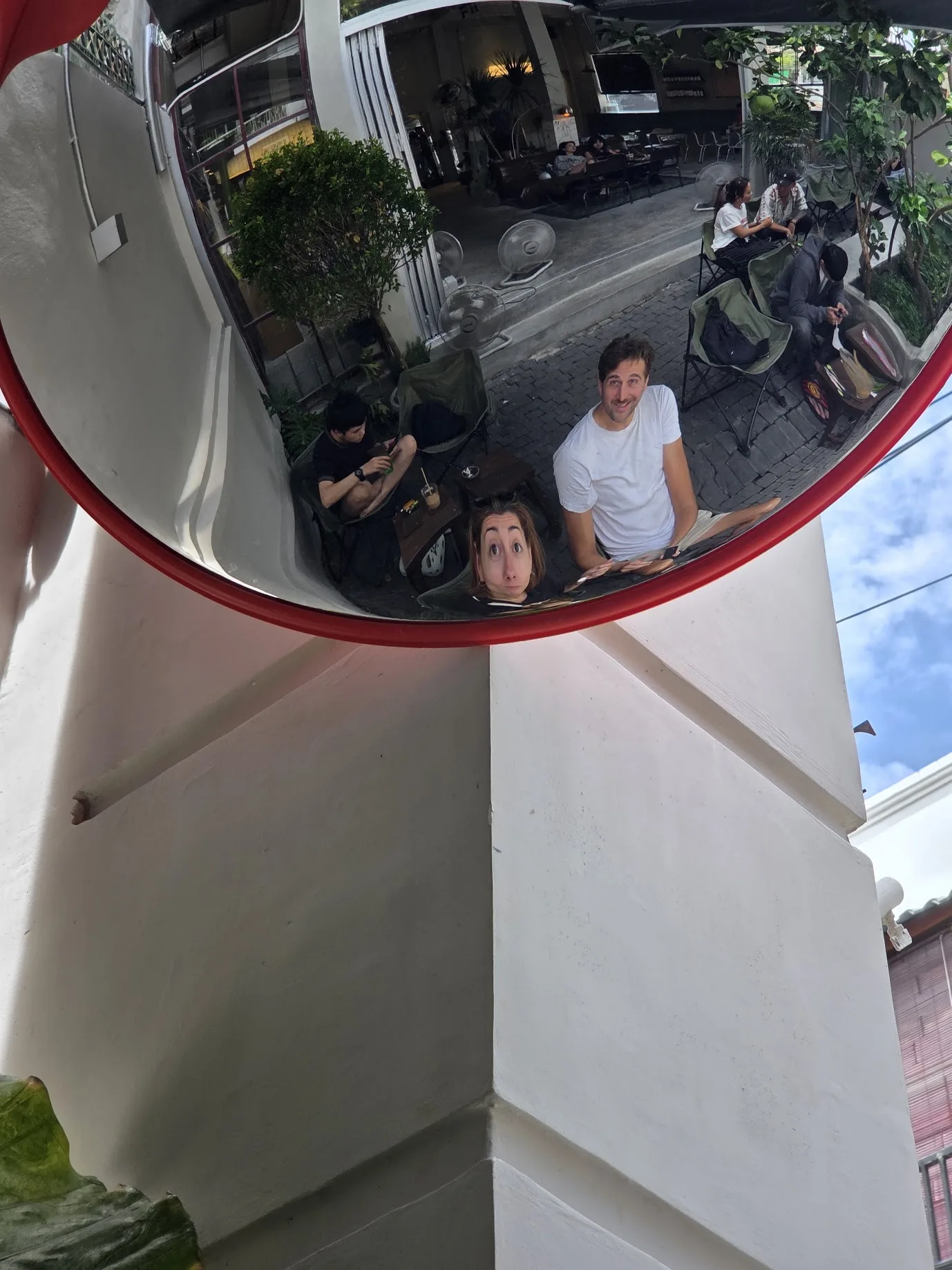Daniel and Noela looking up into a convex street mirror in Nha Trang